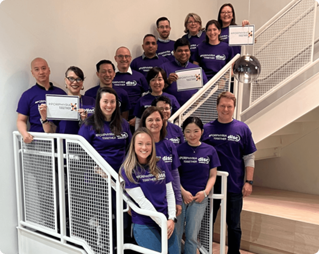 Group photo of volunteers gathered on a staircase wearing purple shirts and holding up signs